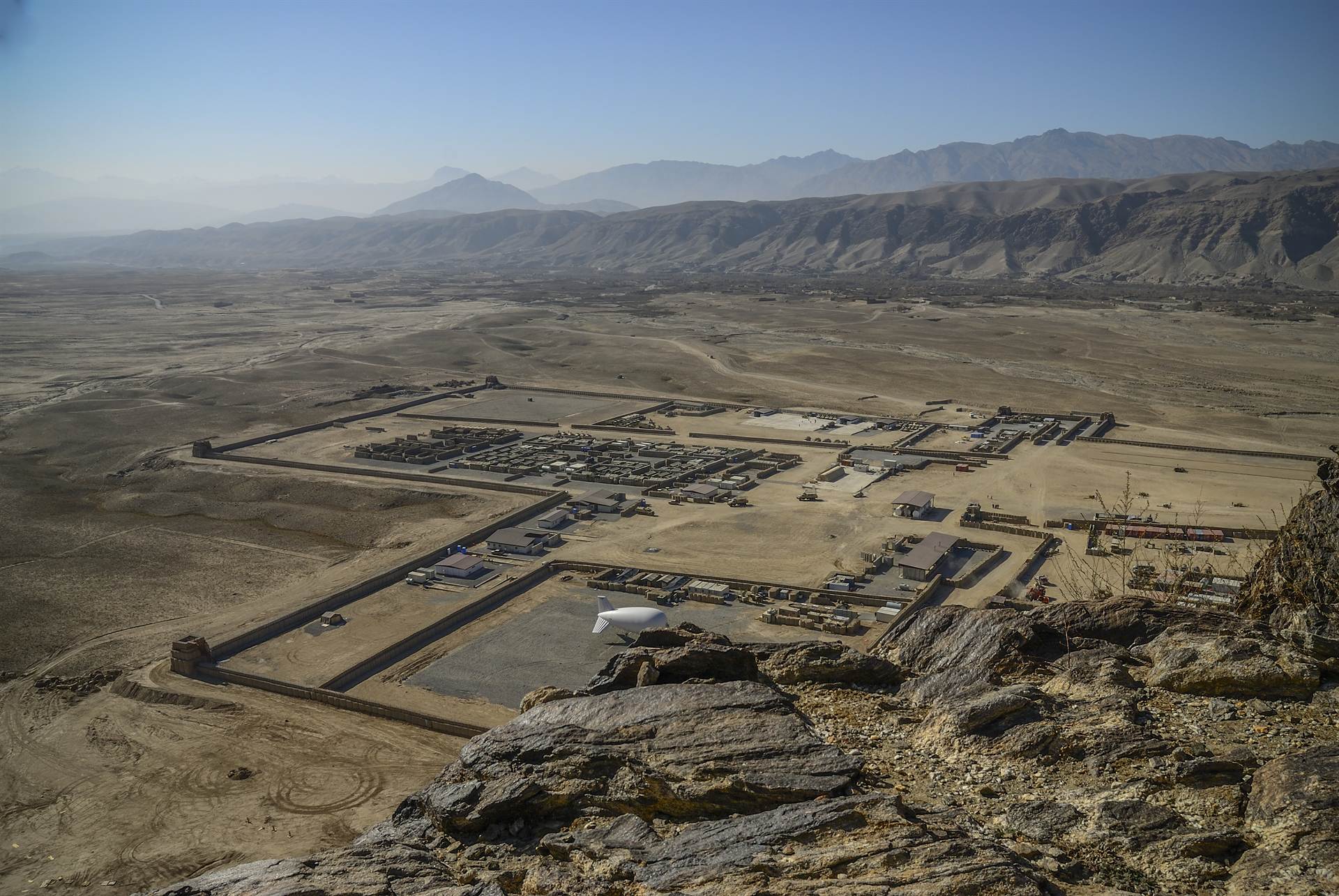 Aerial panorama of a remote base camp supported in an austere mountain-desert environment