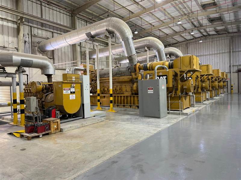 Row of large CAT generator sets inside a Synerje-supported power plant facility