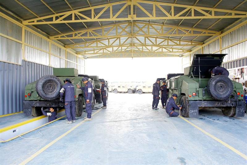 Technicians servicing tactical vehicles in a covered maintenance bay