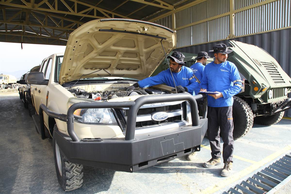 Synerje technicians in company uniform performing a documented engine-bay inspection on a light truck