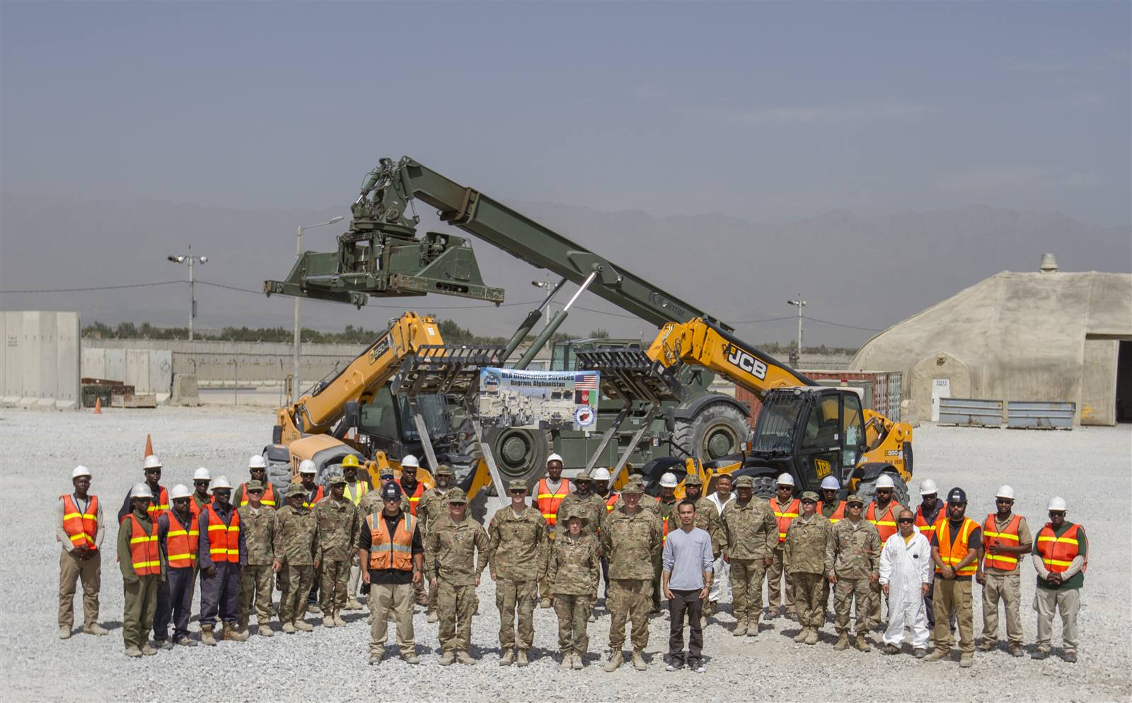 Synerje crew and U.S. Army personnel standing together in front of telehandlers at a DLA Disposition Services site, Bagram, Afghanistan