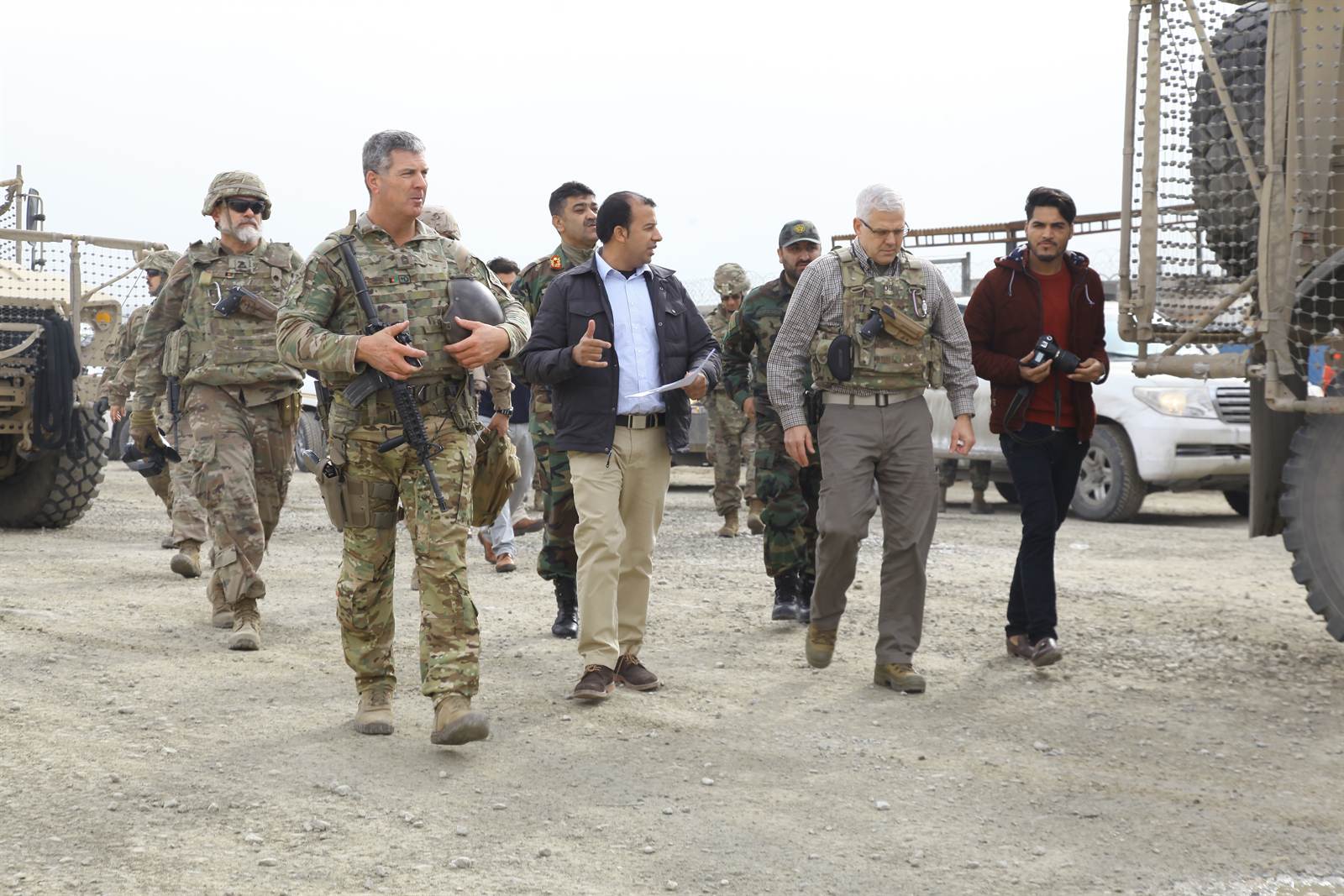 Synerje program staff walking and conferring with U.S. military clients at a vehicle yard